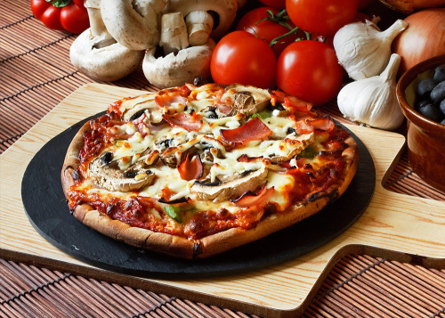 ham and mushroom wood fired pizza on a wooden serving plate