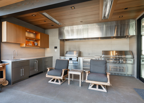 Modern fully equipped outdoor kitchen and lounge area designed for cooking and entertaining outdoors.